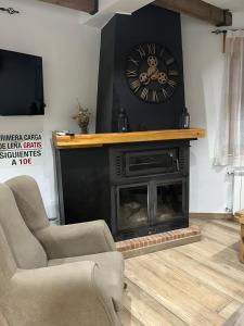 a living room with a fireplace with a clock on the wall at Vivienda Turistica Alojamiento Rural CASA IRENE II in Segura de la Sierra