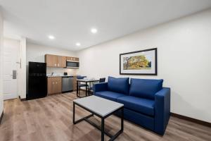 a living room with a blue couch and a kitchen at MainStay Suites Raleigh North in Raleigh