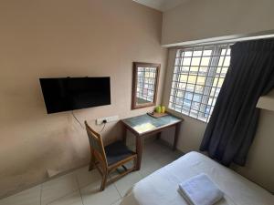 スレンバンにあるAngsa Hotelのデスク、ベッド、テレビが備わる客室です。