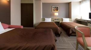 una habitación de hotel con dos camas y una silla en New Biwako Hotel, en Zeze-Awazumachi