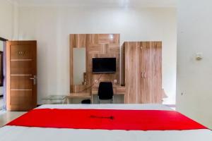 een slaapkamer met een rode deken op een bed bij RedDoorz near Tugu Bandara Sulthan Thaha Jambi in Sultan Thaha Airport