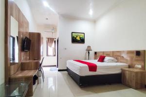 een hotelkamer met een bed en een bureau bij RedDoorz near Tugu Bandara Sulthan Thaha Jambi in Sultan Thaha Airport +18 foto's