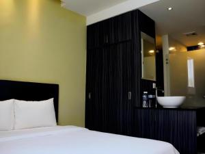 a bedroom with a bed and a bathroom with a sink at Zotel Business & Leisure Hotel in Kampong Tabuan +76 photos