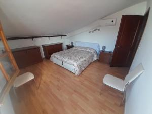 a bedroom with a bed and two white chairs at Appartement à 300 m de la mer in Nughedu Santa Vittoria