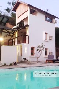 a villa with a swimming pool in front of a house at Matappa Guest House in Pulau Sarang