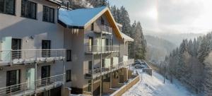 a building with snow on the ground next to a mountain at Apartmán Dub in Golčŭv Jeníkov