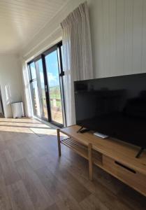 een woonkamer met een grote televisie en een houten tafel bij Forest View Farm Stay in Pirongia