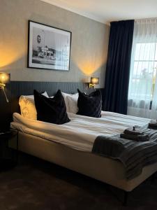 a large bed with black pillows in a bedroom at Central Hotellet Tierp in Tierp