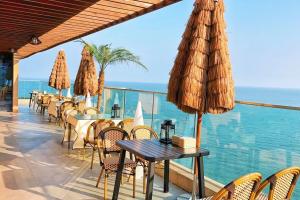 een restaurant met tafels en stoelen en uitzicht op de oceaan bij Qingdao Momer Cliff Ocean View Villas in Qingdao