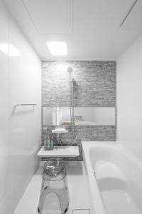 une salle de bain blanche avec une baignoire et un lavabo dans l'établissement Sasameyuki, à Furano
