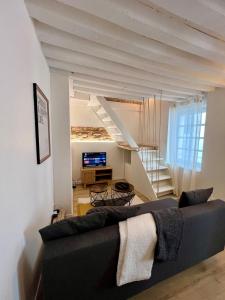 Una sala de estar con un sofá y una escalera. en Perchoir Riboud - Coeur de ville, en Bourg-en-Bresse