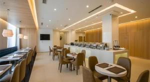 沈阳Jinjiang Metropolo Hotel Shenyang Country Garden Datong Lake Subway Station Branch的有桌椅和酒吧的餐厅