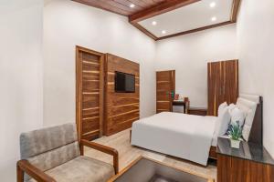 a bedroom with a bed and a chair and a television at Country Inn Premier Pacific Mall Road Mussoorie in Mussoorie