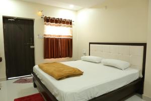 a bedroom with a large bed with a brown blanket on it at SV Grand in Proddatūr