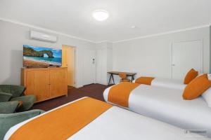 a hotel room with two beds and a television at Mid City Motel Warrnambool in Warrnambool