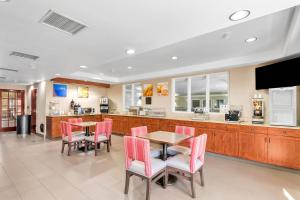 レイクウッドにあるComfort Suites Lakewood - Denverのピンクの椅子とテーブルとカウンターのあるキッチン