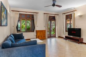 a living room with a blue couch and a tv at Luxurious 3BRVilla Domaine Mui Ne with Pool & Tennis Court Access in Ấp Phú Tịnh (2)