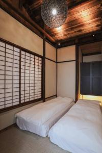 deux lits dans une chambre avec plafonds et fenêtres en bois dans l'établissement 東京下町生活, à Tokyo