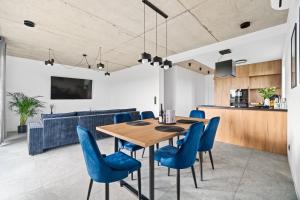 a dining room with a wooden table and blue chairs at Jack Apartments- Apartamenty z garażem in Kamień Śląski