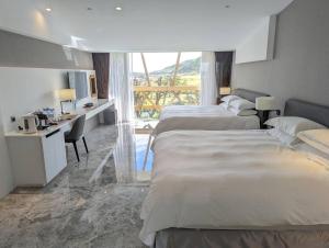 a hotel room with two beds and a desk and a kitchen at Volando Kenting in Hengchun