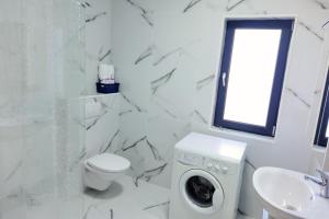 a white bathroom with a washing machine and a sink at Apartament via carmina in Văleni +5 photos