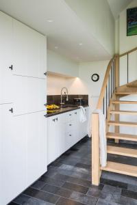 a kitchen with white cabinets and a staircase at Sint-Coryn in Reninge
