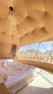 a bed in a room with a view of the desert at Wadi rum sky luxury in Wadi Rum