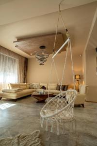 a living room with a hanging chair and a couch at Zsizell Lux Apartman in Kanjiža