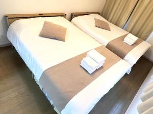 two beds in a hotel room with towels on them at Camelot House in Fukuoka