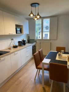 Una cocina con gabinetes blancos y una mesa y sillas. en MAISON GERMÈS - CENTRAL & STANDING - Appartements traversants - Lits 180 King Size - Linge de lit et de toilette inclus - Parking à proximité, en Luchon