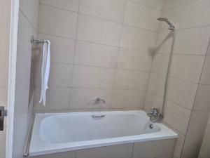 a white bath tub in a white tiled bathroom at Elegant Bliss -2 bedroomed at Dainfern, in Fourways, Sandton in Fourways +18 photos