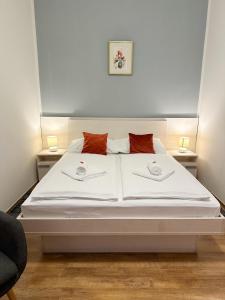 a bedroom with a white bed with two pillows on it at Rooms Lidija in Zagreb