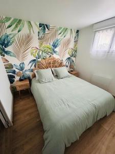 a bedroom with a large bed with a tropical wallpaper at Appartement au calme in Saint-Denis-sur-Loire