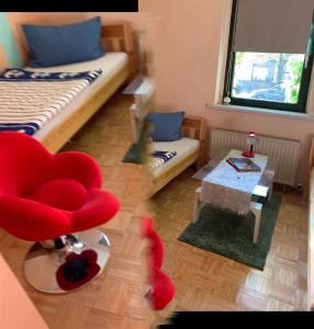ein Wohnzimmer mit einem roten Stuhl und einem Tisch in der Unterkunft Finca Sommerfeld 2-Zimmerhaus mit Terrasse und Garten in Kremmen
