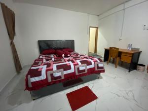 a bedroom with a bed and a desk and a red blanket at BMC HomeStay in Sebungsungai