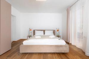 a bedroom with a bed with white sheets and wood floors at Villa Hietzing in Vienna