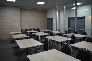 an empty classroom with wooden tables and chairs at Triumph Hotel in Obninsk