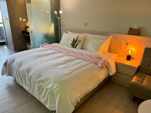 um quarto com uma grande cama branca e um candeeiro em 漫遊文旅溫泉宅ㄧ山海景觀陽台房ㄧ晚上6點入住ㄧ晚進晚退一21小時睡飽飽方案 em Toucheng