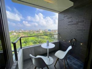 uma varanda com mesa e cadeiras e uma grande janela em 漫遊文旅溫泉宅ㄧ山海景觀陽台房ㄧ晚上6點入住ㄧ晚進晚退一21小時睡飽飽方案 em Toucheng