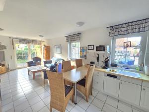 Nordseeferienhaus Ehlers في نيسمارزييل: مطبخ وغرفة معيشة مع طاولة وكراسي