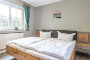 JagdhausにあるJagdhaus Schwinkelsmoorの白いシーツと枕が付いた大きなベッドのある寝室