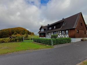 Ein braun-weißes Haus mit einem Feld und Bäumen in der Unterkunft Ferienwohnung Beim Schorsch in Schannenbach