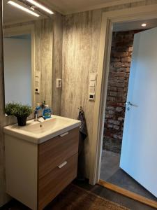 baño con lavabo, espejo y pared de ladrillo en Apartment Senja, en Senja