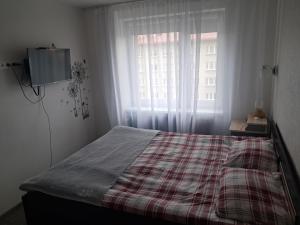 a bedroom with a bed with a plaid blanket and a window at Tallinna mnt 15 Apartament in Narva