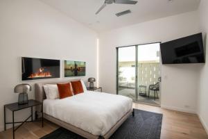 a white bedroom with a bed and a fireplace at Carbon @ Elemento49 Pool Spa Sleeps 16 in Desert Groves Mobile Home Park +32 photos