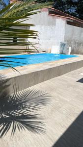 a shadow of a palm tree next to a swimming pool at Chalé Bromélia in São Sebastião