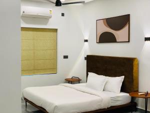 a bedroom with a bed with white sheets and a window at ZAHIR RESIDENCY in Kondotti