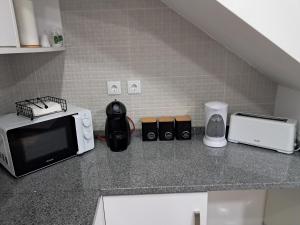 a kitchen with a counter top with a microwave and appliances at Casa do Sardão in Sardoal