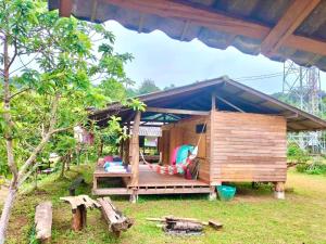 Cette petite maison en bois possède une terrasse couverte dans une cour. dans l'établissement Maewin Farmer Homestay, à Ban Huai Rin