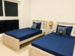 a bedroom with two beds with blue sheets and a window at Fairway Galle in Galle